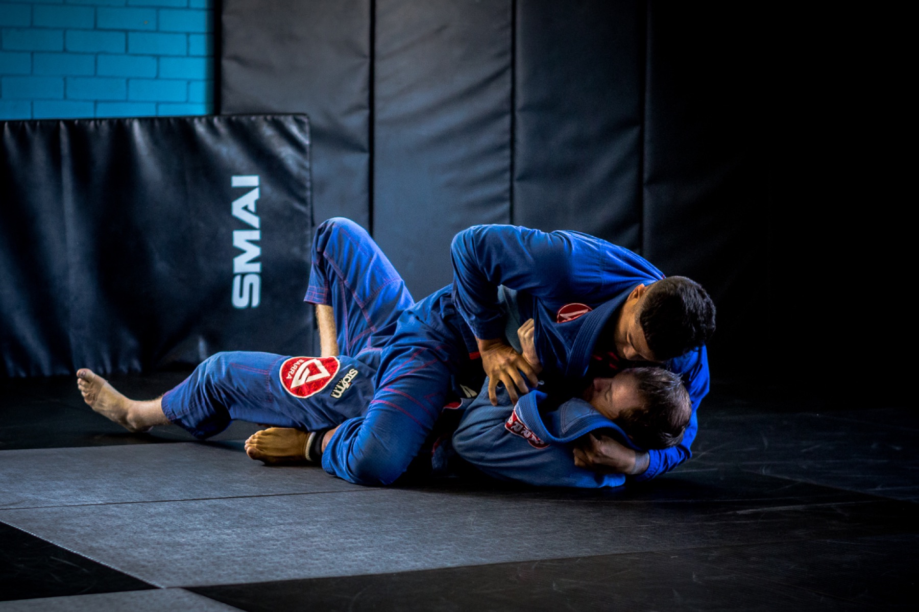 Athletes training together on the mats inside a gym.