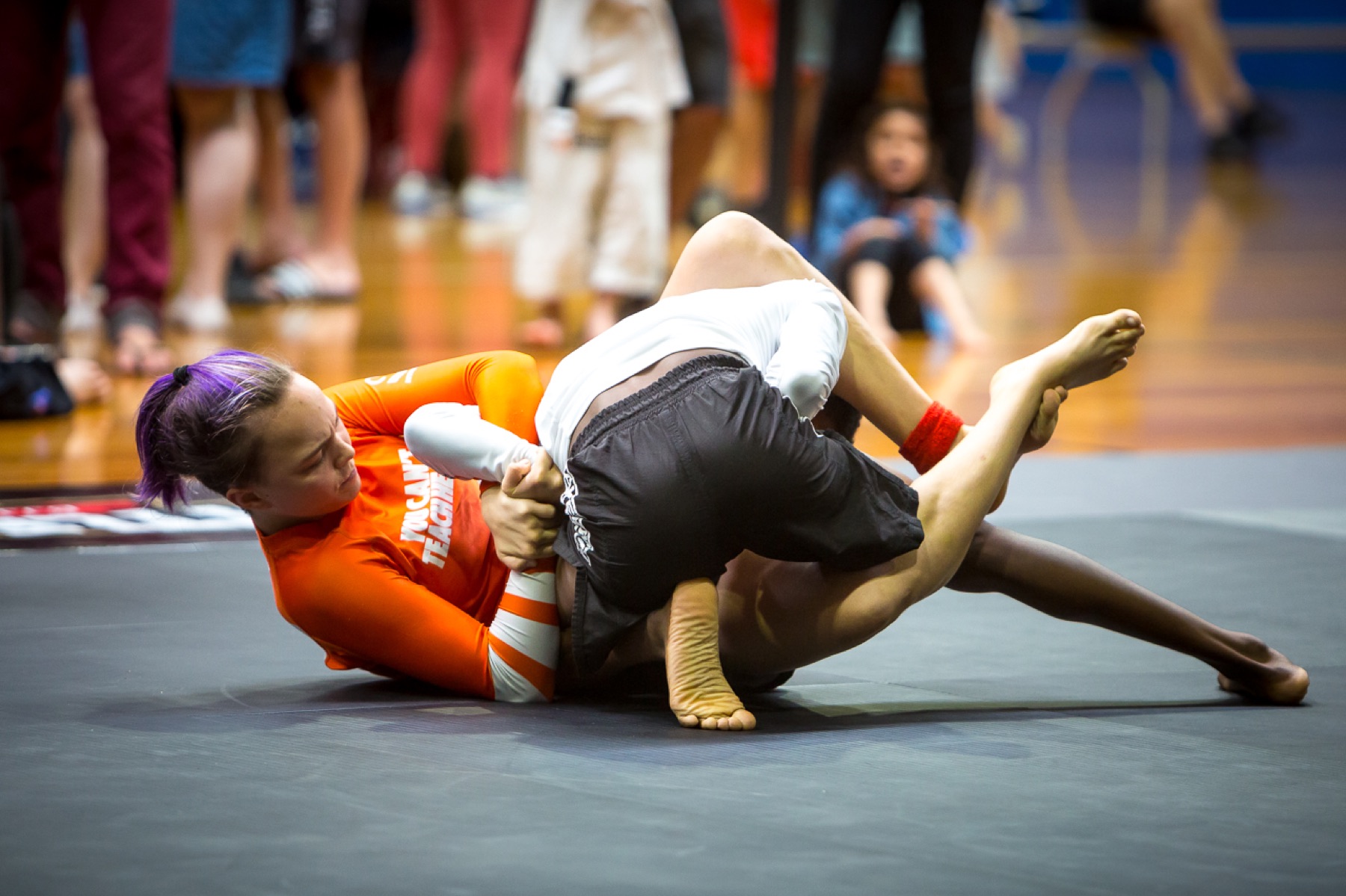Two competitors grappling on the mat during a tournament match.