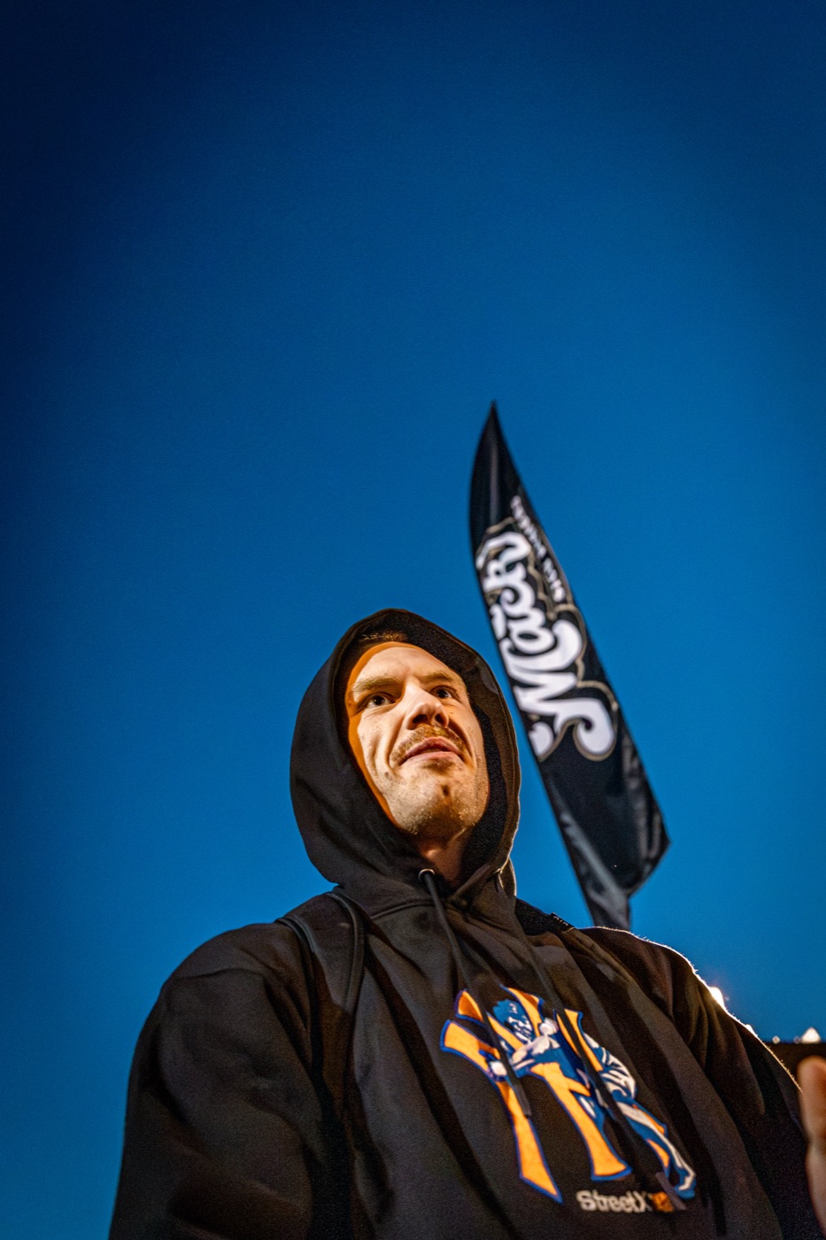 Low-angle blue-hour portrait of a hooded athlete.